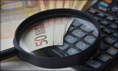 Immagine: foto di una lente di ingrndimento sopra a soldi euro e calcolatrice
