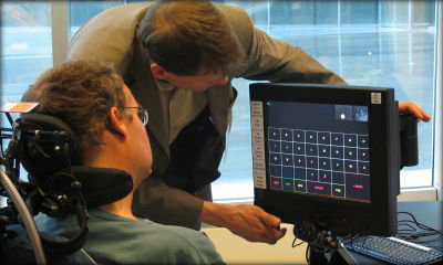 Immagine: foto di persona con disabilità motoria davanti a un ausilio tecnologico