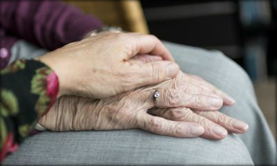 Immagine: mani di persona anziana circondate da mani di persona più giovane