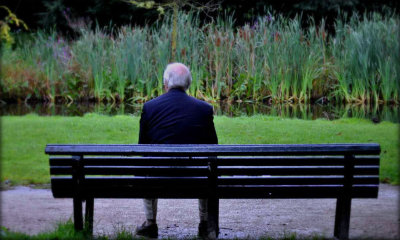 Persona anziana seduto su una panchina, di spalle