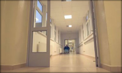 Immagine: foto da lontano di persona su sedia in un corridoio di ospedale